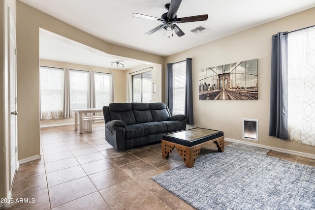 tiled living area with ceiling fan and baseboards