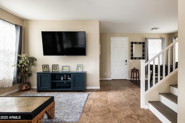 living area featuring stairs and baseboards