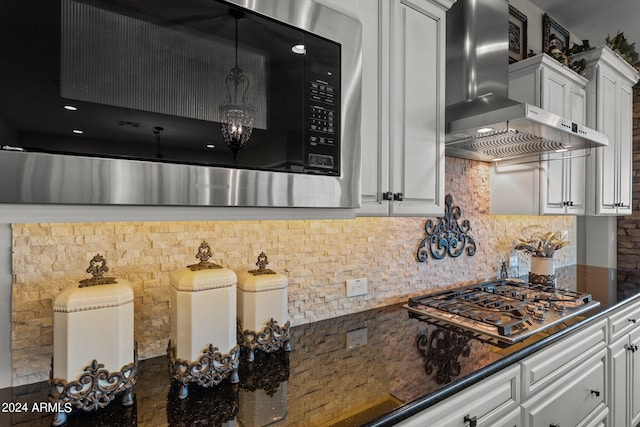 kitchen with stainless steel appliances, tasteful backsplash, wall chimney range hood, and white cabinets