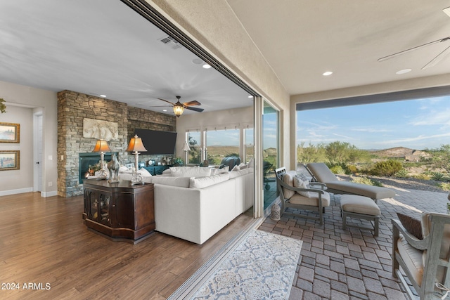 sunroom featuring ceiling fan and a fireplace