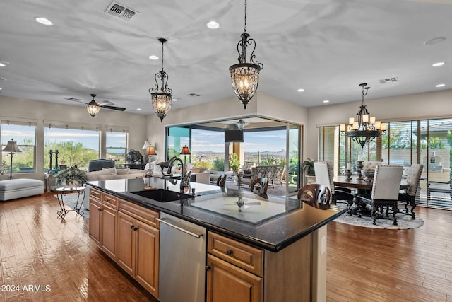 kitchen with hardwood / wood-style flooring, pendant lighting, sink, and a center island with sink