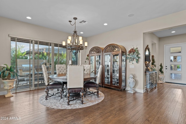 dining area featuring dark wood-type flooring and an inviting chandelier