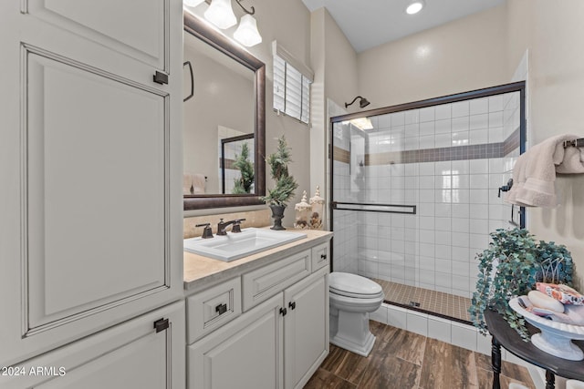 bathroom featuring wood-type flooring, toilet, an enclosed shower, and vanity