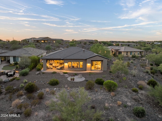 back house at dusk with a patio area