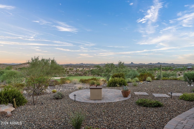 yard at dusk featuring a mountain view and a patio area