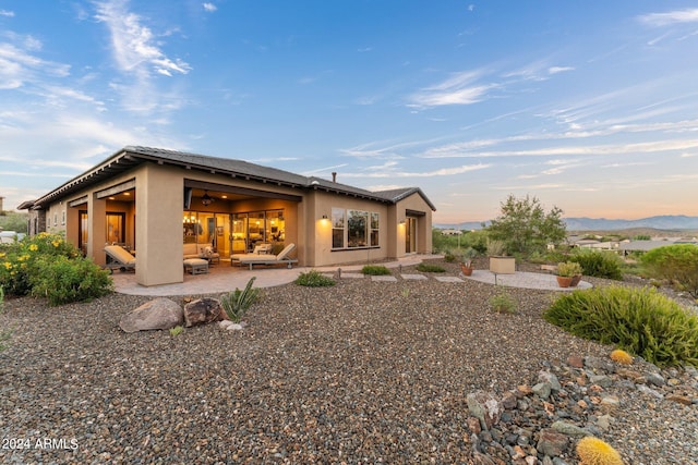 back house at dusk with an outdoor hangout area and a patio