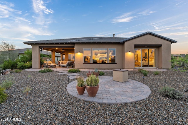 back house at dusk with ceiling fan and a patio area