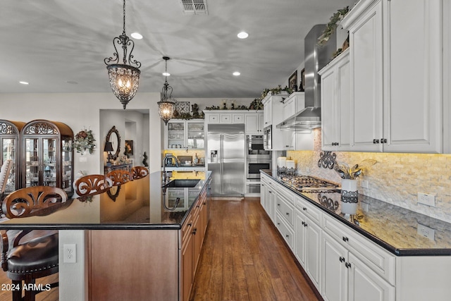 kitchen featuring sink, hanging light fixtures, stainless steel appliances, white cabinets, and a large island with sink