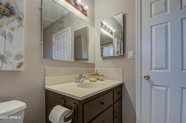 bathroom featuring vanity, decorative backsplash, and toilet