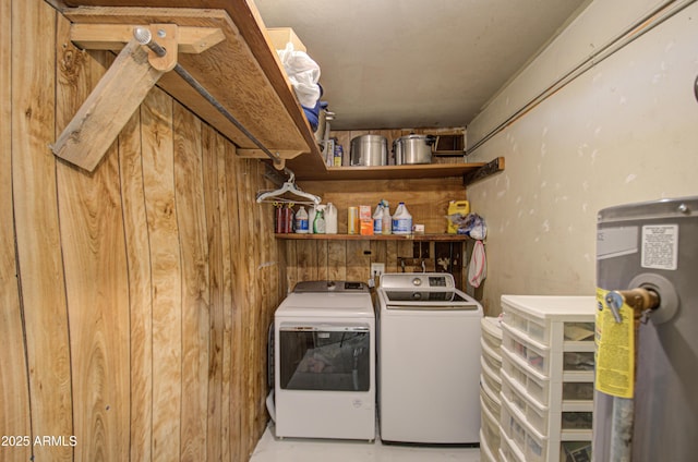 washroom featuring wood walls, washer and clothes dryer, and gas water heater