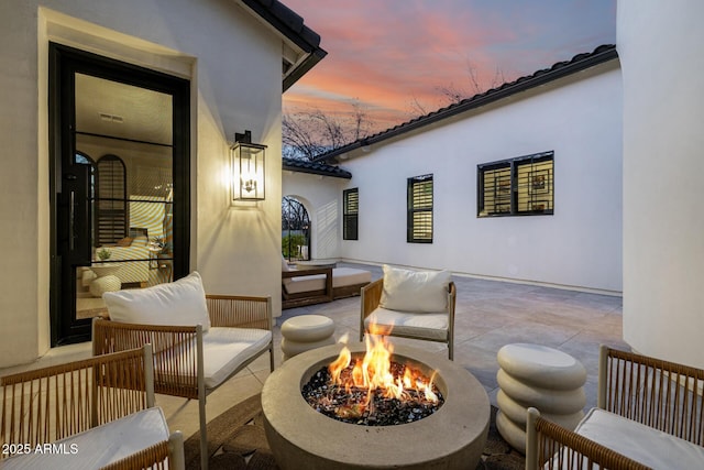 patio terrace at dusk featuring an outdoor living space with a fire pit