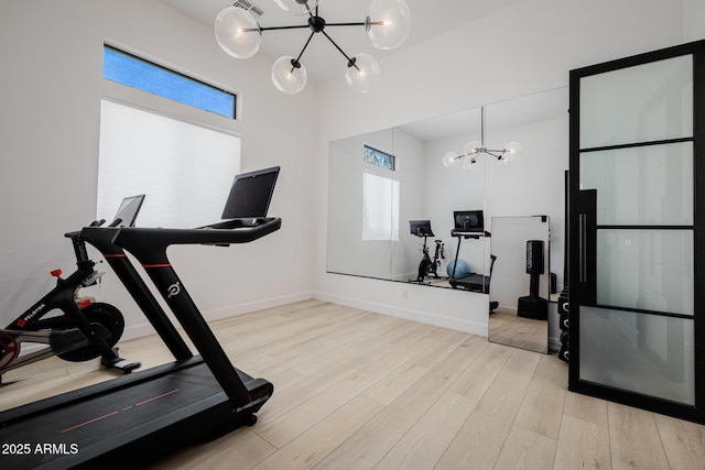 workout area featuring an inviting chandelier and light hardwood / wood-style flooring