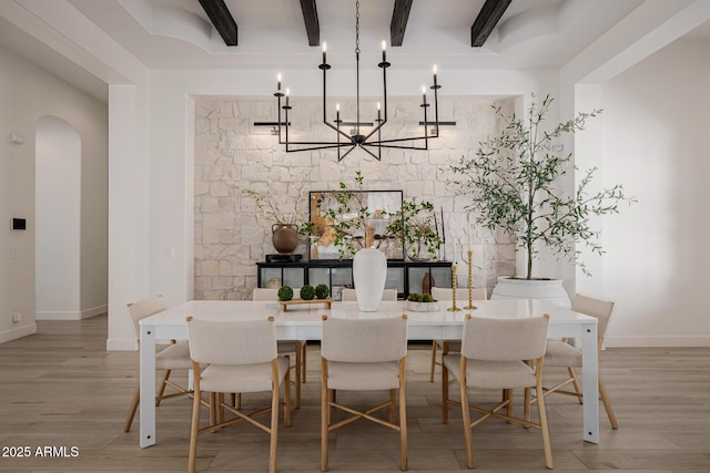 dining space with light hardwood / wood-style floors, beamed ceiling, and a notable chandelier