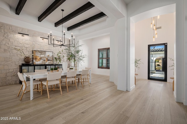 dining space with an inviting chandelier, a high ceiling, light hardwood / wood-style flooring, and beamed ceiling