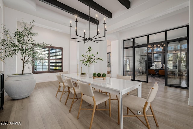 dining room featuring light wood-type flooring, an inviting chandelier, and beam ceiling