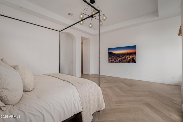 bedroom featuring a tray ceiling and light parquet flooring