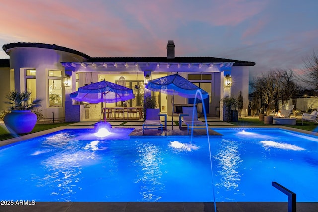 pool at dusk featuring a patio and pool water feature