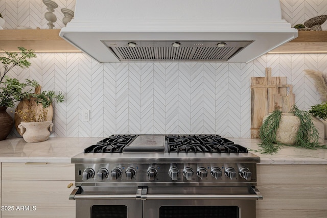 kitchen featuring tasteful backsplash, light stone countertops, range with two ovens, and ventilation hood