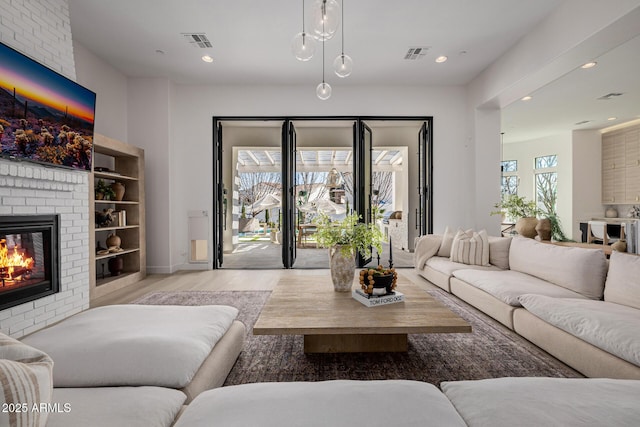 living room featuring a brick fireplace and light wood-type flooring