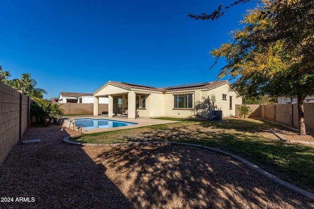 rear view of house featuring a patio, a fenced in pool, and a lawn