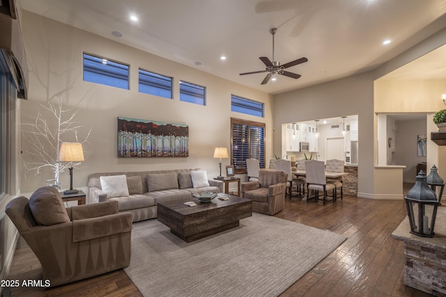 living room with a high ceiling, dark hardwood / wood-style floors, and ceiling fan