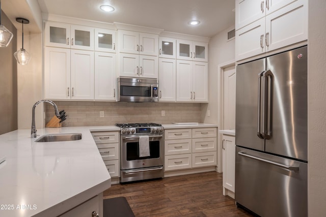 kitchen featuring sink, white cabinets, pendant lighting, stainless steel appliances, and backsplash