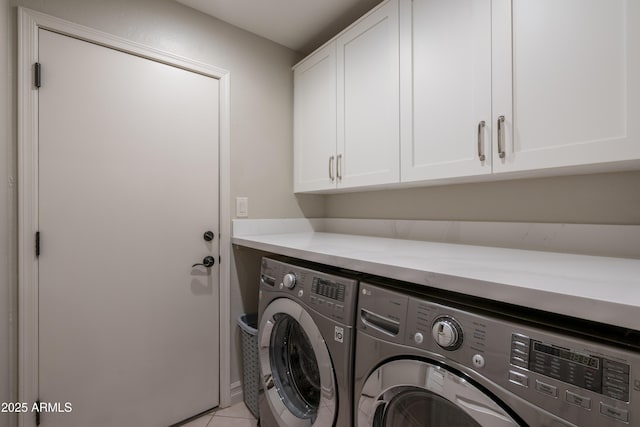 laundry room featuring cabinets, washer and dryer, and light tile patterned floors