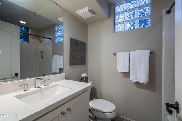 bathroom with vanity, a tile shower, and toilet