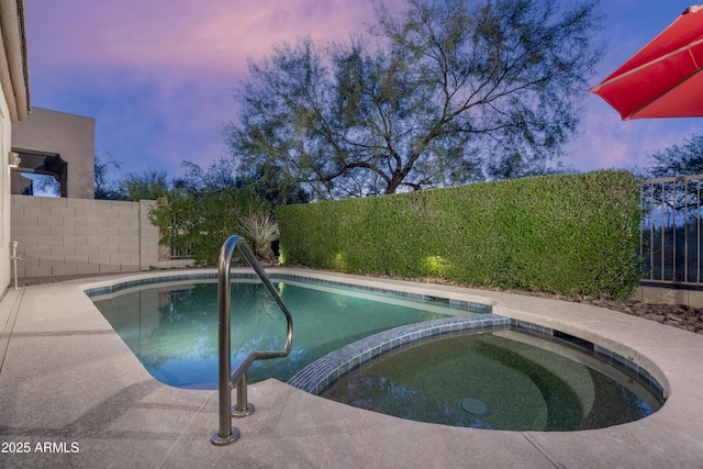 pool at dusk featuring an in ground hot tub