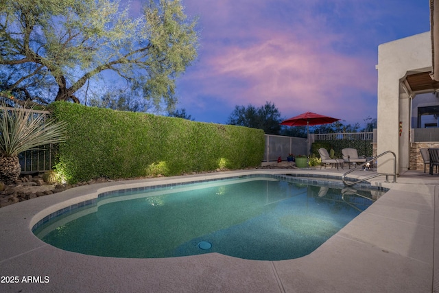 pool at dusk with a patio area