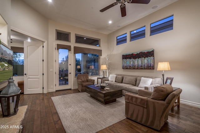 living room with a high ceiling, ceiling fan, and dark hardwood / wood-style flooring