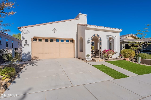 mediterranean / spanish home featuring a front lawn and a garage