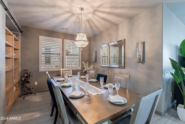 dining area featuring a chandelier, a barn door, and light hardwood / wood-style flooring