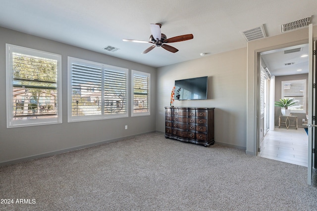 unfurnished living room with light colored carpet and ceiling fan