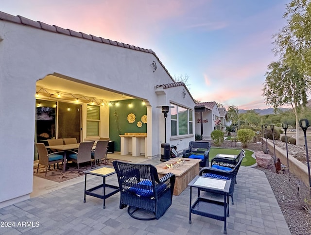 patio terrace at dusk with an outdoor living space with a fire pit