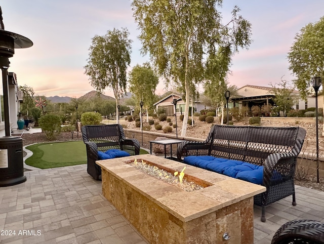 patio terrace at dusk featuring a mountain view and an outdoor living space with a fire pit