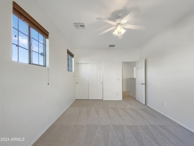 unfurnished bedroom featuring ceiling fan, a closet, and light colored carpet