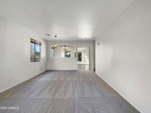 unfurnished living room featuring light colored carpet and an inviting chandelier