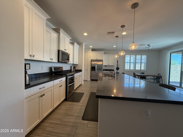 2727 N Acacia Way, Buckeye, AZ 85396 - kitchen featuring appliances with stainless steel finishes, healthy amount of natural light, dark countertops, a sink, and recessed lighting