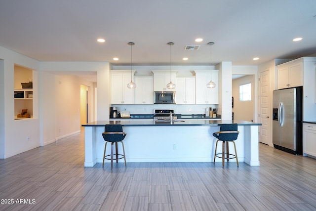 2727 N Acacia Way, Buckeye, AZ 85396 - kitchen with appliances with stainless steel finishes, dark countertops, a breakfast bar, an island with sink, and recessed lighting