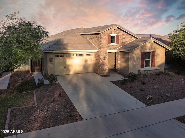 2727 N Acacia Way, Buckeye, AZ 85396 - view of front of house with a garage, driveway, stone siding, a tiled roof, and stucco siding