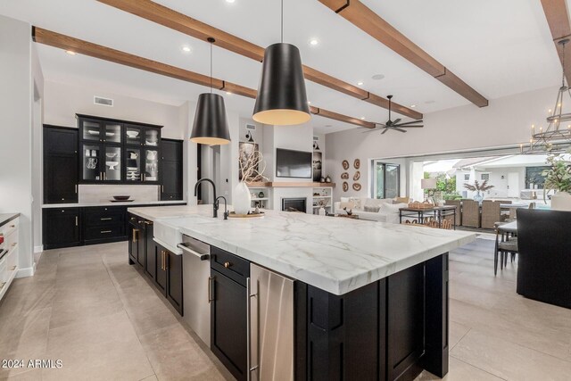 kitchen with a large island, decorative light fixtures, beam ceiling, and sink