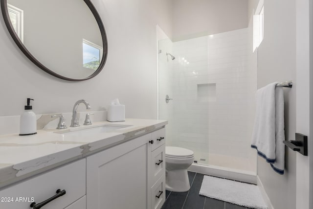 bathroom featuring tile patterned flooring, a tile shower, vanity, and toilet