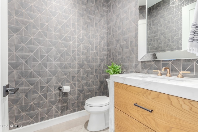 bathroom with tile patterned floors, toilet, decorative backsplash, vanity, and tile walls