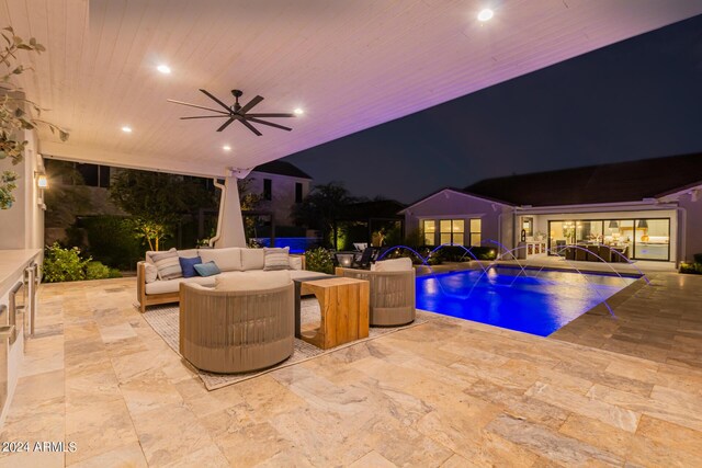 pool at twilight featuring pool water feature, ceiling fan, outdoor lounge area, and a patio