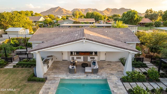 back house at dusk featuring area for grilling, a mountain view, a patio area, and an outdoor living space