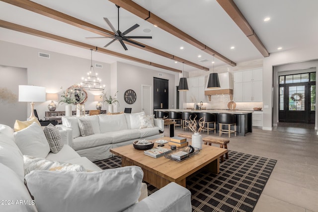 living room with ceiling fan with notable chandelier and beam ceiling