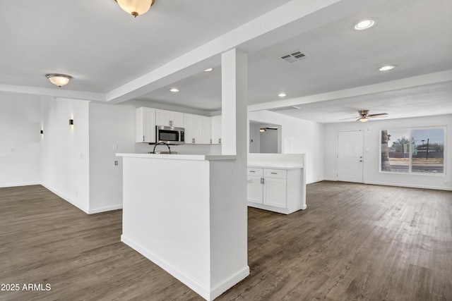 kitchen with dark wood finished floors, stainless steel microwave, visible vents, open floor plan, and white cabinetry