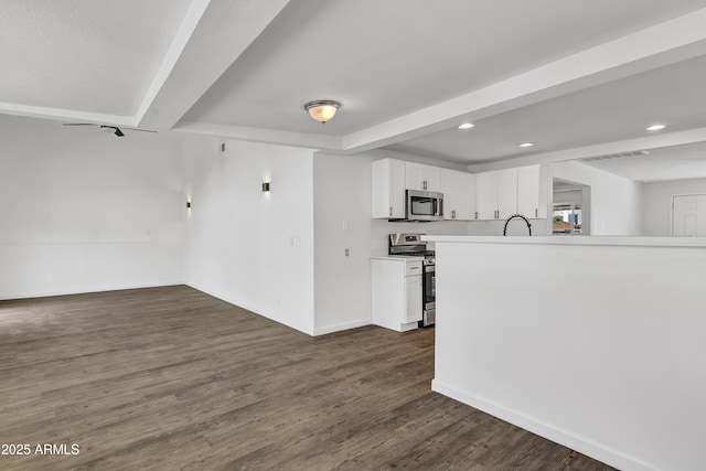 kitchen with dark wood-style flooring, stainless steel appliances, light countertops, white cabinetry, and recessed lighting