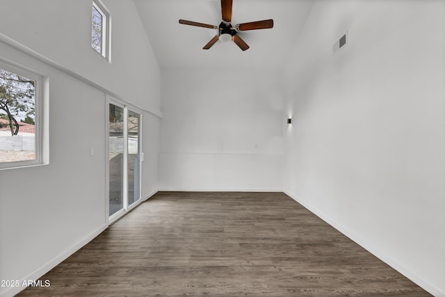 unfurnished room with visible vents, dark wood-type flooring, a high ceiling, and baseboards